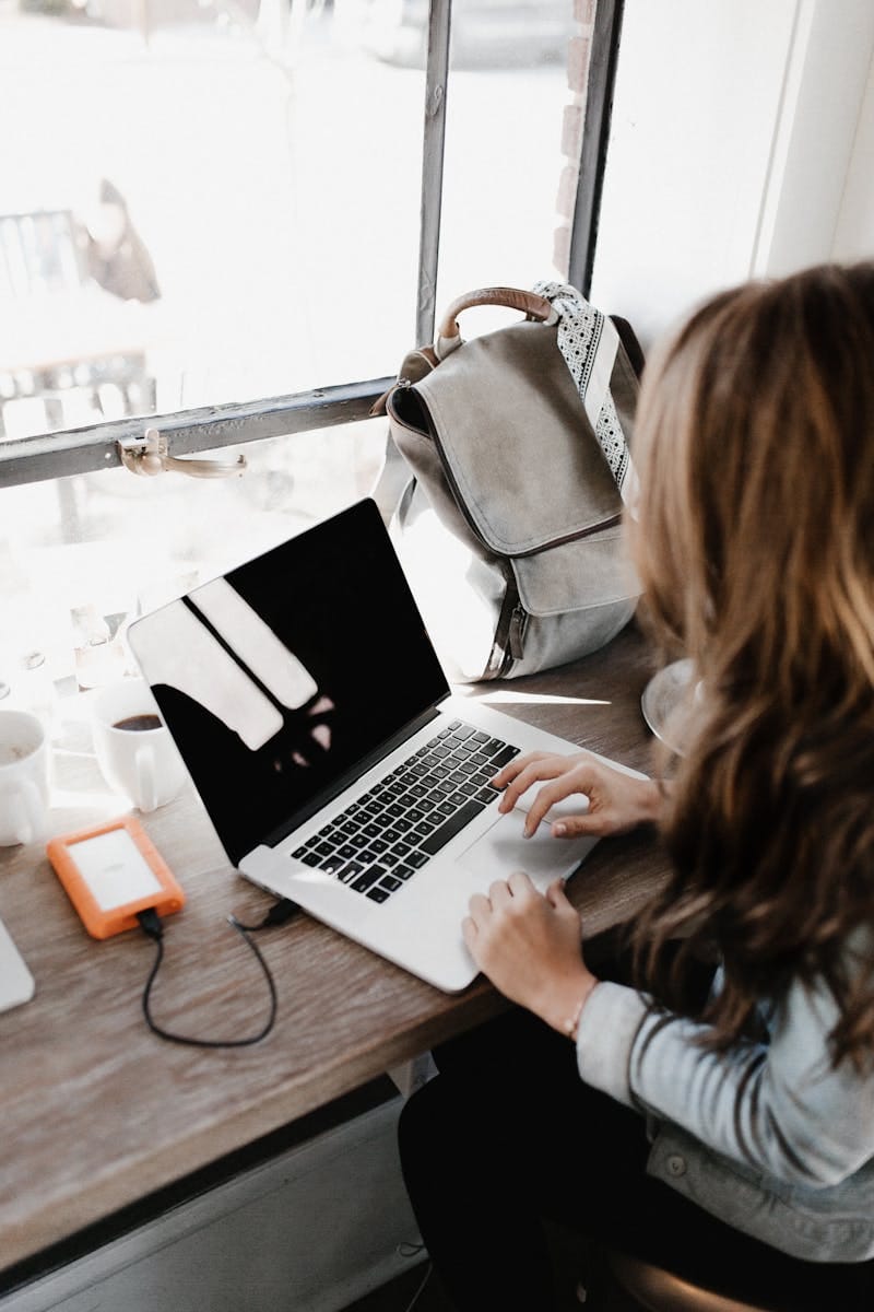 A confident midlife woman smiling while managing her budget on a laptop with a cup of coffee.
