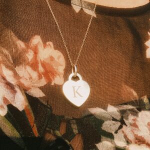 a woman wearing a necklace with a heart shaped pendant
