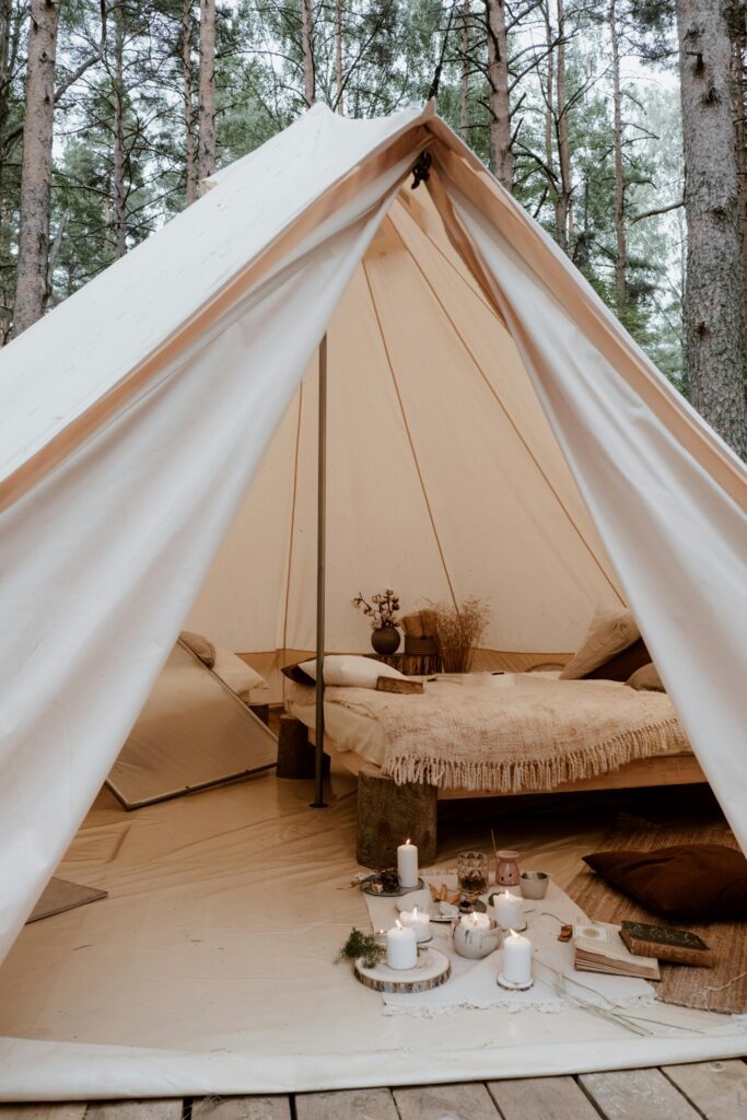 Inviting glamping setup with cozy tent and candles nestled in a serene forest.