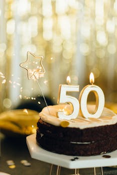 Celebrate a 50th birthday with a chocolate cake featuring golden candles and a sparkling star topper.