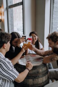 Young adults toasting with beer at a cozy bar setting, enjoying time together.