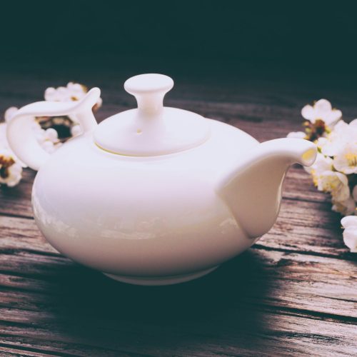 a white tea pot sitting on top of a wooden table